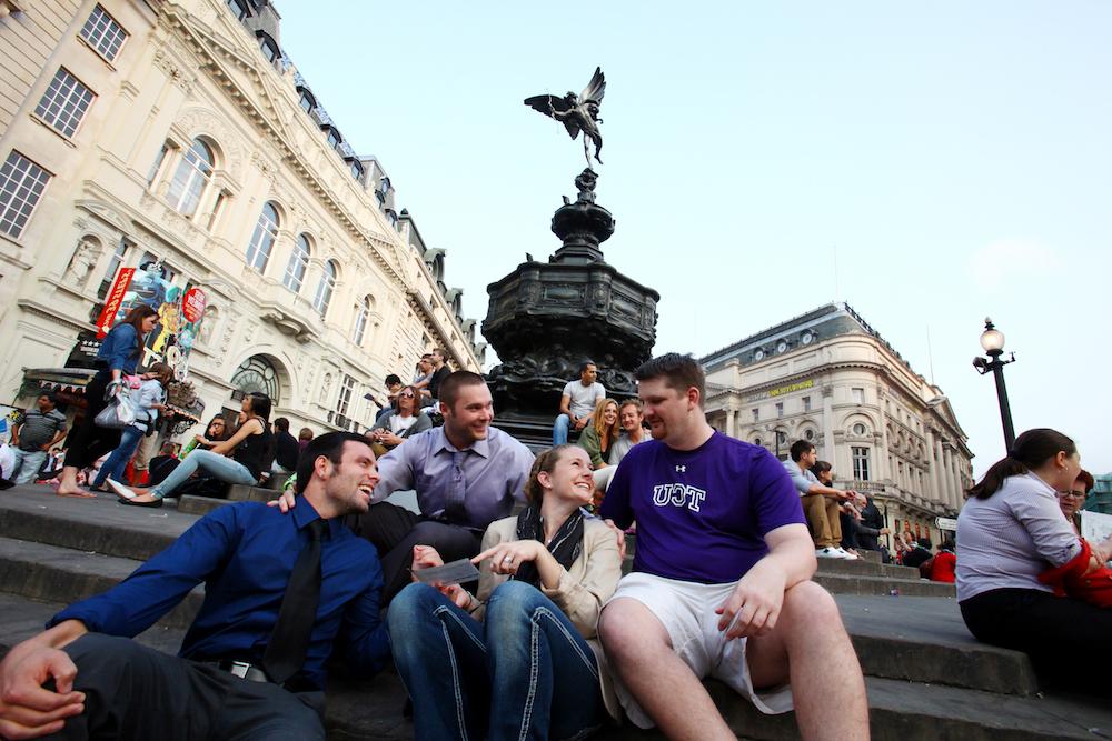 A small group of TCU students gather in front of an ornate fountain in a piazza.